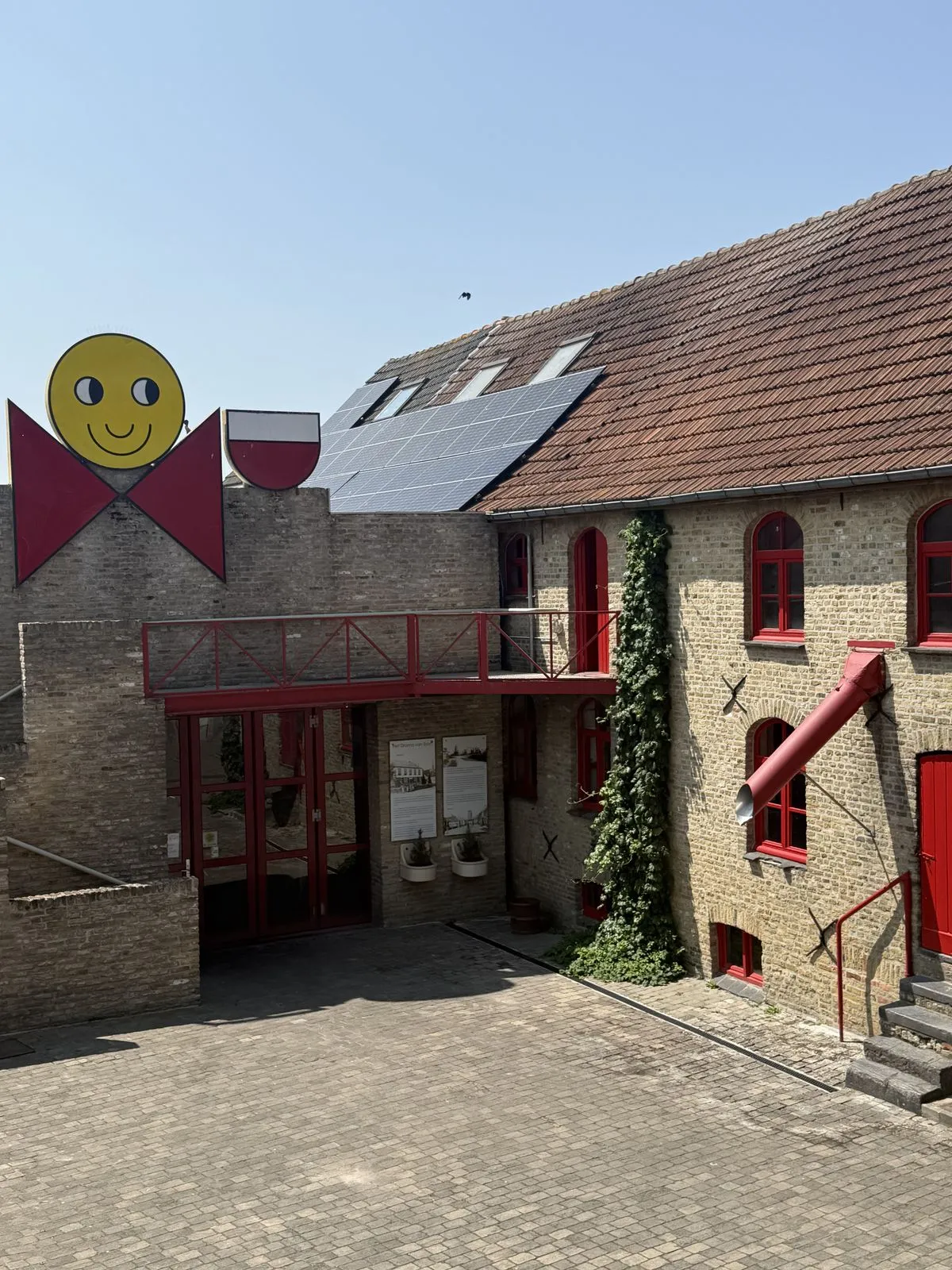 De binnenkoer van De Dolle Brouwers met het smiley-mannetje op het dak en rode vensters
